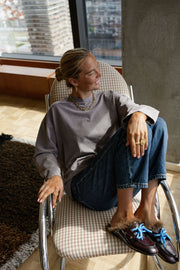 T-shirt loose à col rond porté par une femme, assise, sur une chaise, chaussures bleues