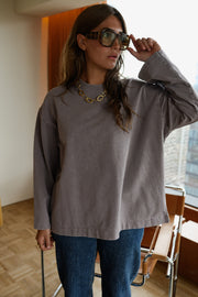 T-shirt loose à col rond porté par une femme, vue rapprochée, main sur les lunettes