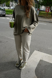 T-shirt loose à manches longues porté par une femme, en marchant, pantalon clair, baskets, rue
