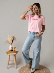 T-shirt en coton extensible porté par une femme, vue de trois-quarts, main dans les cheveux, jean large