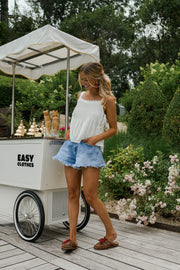 Top dentelle à col carré porté par une femme, silhouette entière, short en jean, de face