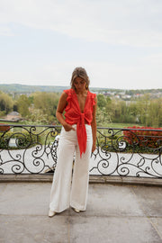 Top volanté à col V porté par une femme, silhouette entière, balustrade, de loin