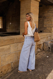 Top fluide effet lin blanc porté par une femme, vue de dos, muret, jean
