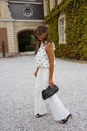 Top à pois effet ballon porté par une femme, silhouette entière, sac noir, pantalon blanc
