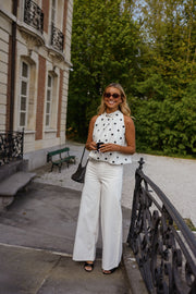 Top à pois effet ballon porté par une femme, silhouette entière, balustrade, pantalon blanc