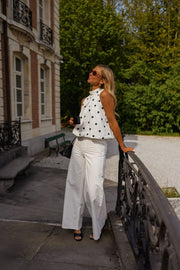 Top à pois effet ballon porté par une femme, silhouette entière, balustrade, sac