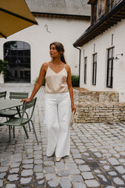 Top à fines bretelles ajustables porté par une femme, silhouette entière, terrasse, pantalon blanc