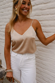 Top à fines bretelles ajustables porté par une femme, vue de trois-quarts, pantalon blanc, sourire