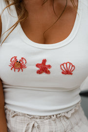 Top moulant à motif coquillage porté par une femme, vue rapprochée, coquillages brodés, décolleté