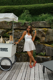Top moulant à motif coquillage porté par une femme, silhouette entière, jupe beige, chariot
