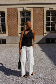 Top asymétrique moulant à nouer porté par une femme, silhouette entière, sac noir, cour