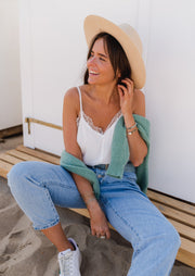 Top à décolleté brodé porté par une femme, assise, banc en bois, jean