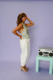 Top dentelle à col drapé porté par une femme, silhouette entière, pantalon blanc, radio