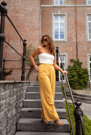 Top bustier effet maille porté par une femme, silhouette entière, escalier, pantalon jaune