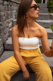 Top bustier effet maille porté par une femme, assise, escalier en pierre, pantalon jaune