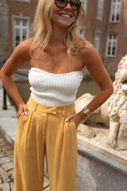 Top bustier effet maille porté par une femme, vue rapprochée, pantalon jaune, mains sur les hanches