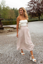 Top bustier effet maille porté par une femme, en marchant, jupe rose, allée de gravier