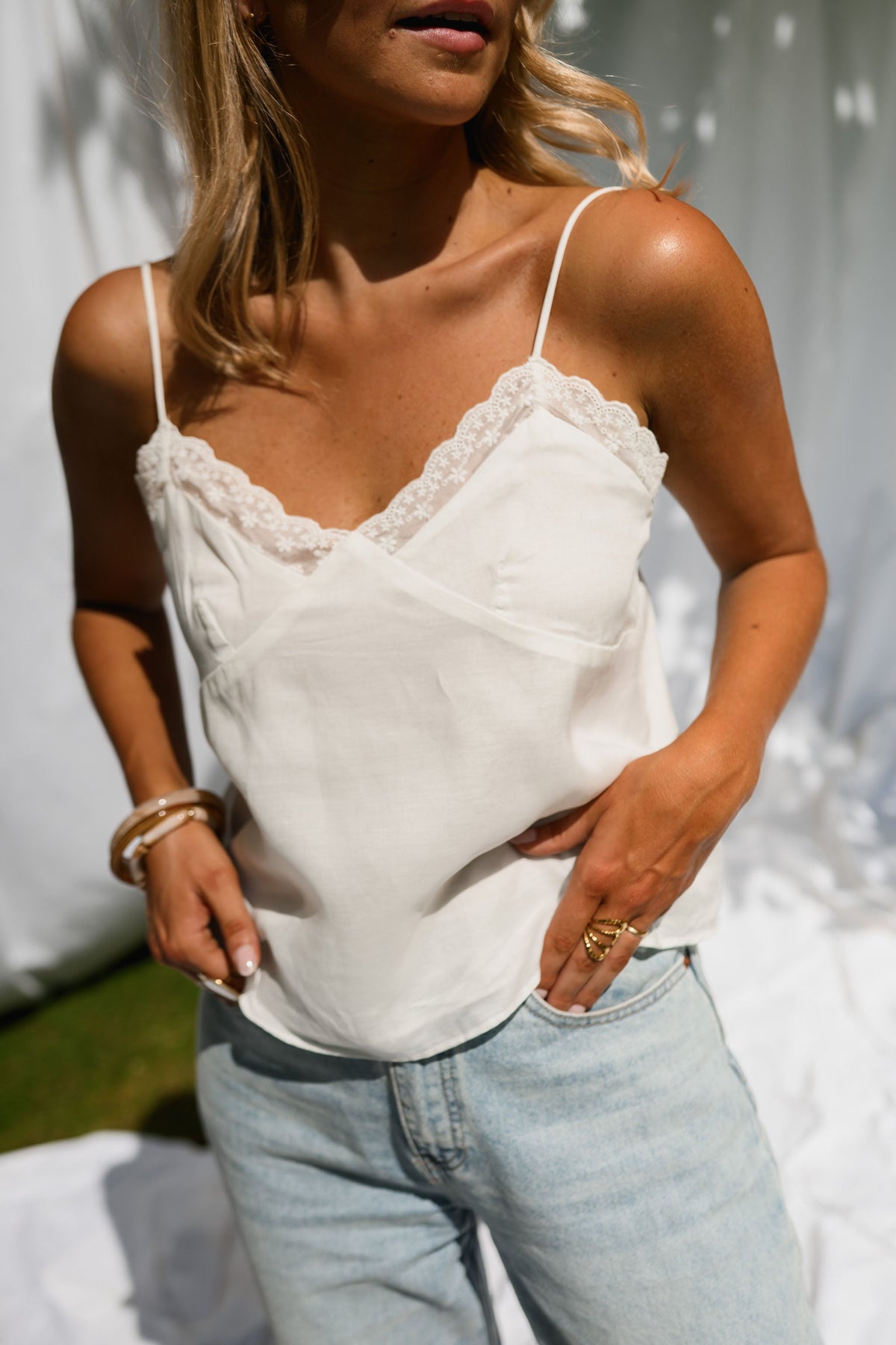 Top dentelle à fines bretelles porté par une femme, vue rapprochée, dentelle, jean clair