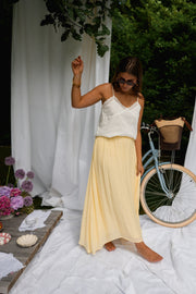Top dentelle à fines bretelles porté par une femme, silhouette entière, jupe jaune, vélo