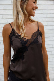 Top asymétrique en dentelle marron porté par une femme, vue rapprochée, dentelle noire, bretelles