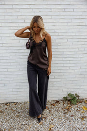 Top asymétrique en dentelle marron porté par une femme, vue de face, gravier, pantalon noir