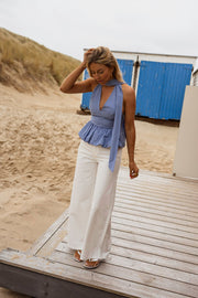 Top vichy dos ouvert porté par une femme, silhouette entière, pantalon blanc, plage