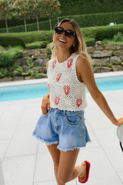 Top crochet à homards brodés porté par une femme, vue de trois-quarts, short en jean, sourire