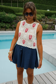 Top crochet à homards brodés porté par une femme, vue de trois-quarts, jupe bleu marine, piscine