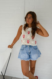 Top crochet à homards brodés porté par une femme, vue de trois-quarts, short en jean, mur blanc