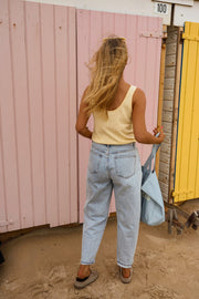 Top fluide effet lin jaune porté par une femme, vue de dos, jean clair, cabine rose