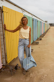 Top fluide effet lin jaune porté par une femme, silhouette entière, jean clair, sac bleu