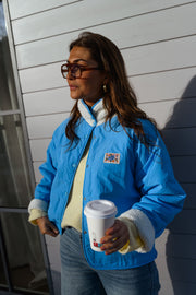 Veste réversible doublée mouton bleue portée par une femme, vue de trois-quarts, côté bleu, cheveux bruns