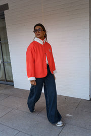 Veste réversible doublée mouton corail portée par une femme, en marchant, côté rouge, jean foncé
