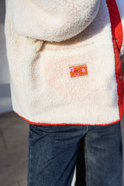 Veste réversible doublée mouton corail portée par une femme, vue rapprochée, poche, étiquette orange