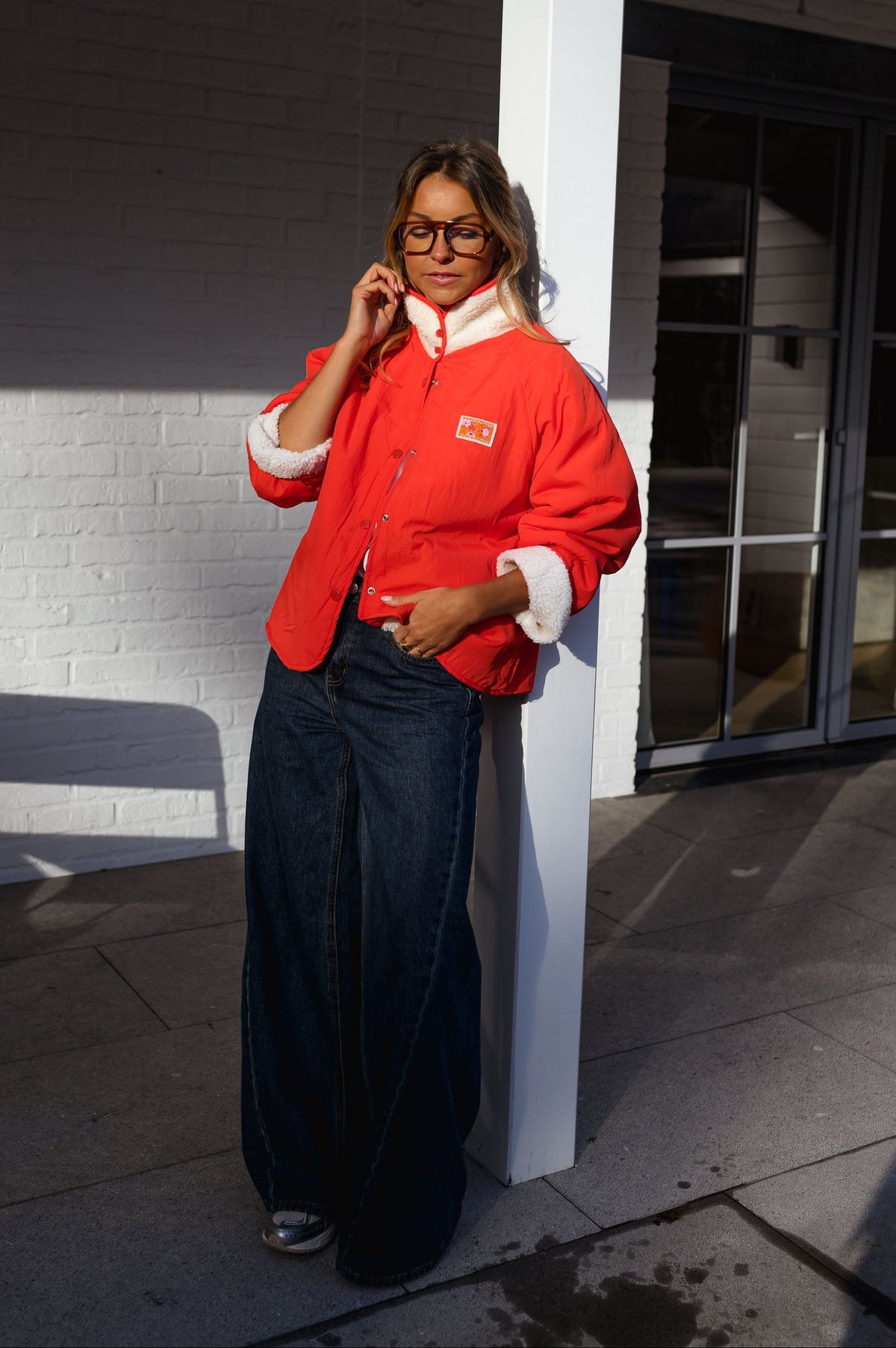 Veste réversible doublée mouton corail portée par une femme, vue de face, côté rouge, porche