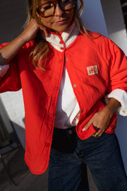 Veste réversible doublée mouton corail portée par une femme, vue rapprochée, côté rouge, mains dans les poches