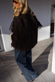 Veste à franges col revers portée par une femme, vue de dos, franges, lunettes de soleil