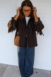 Veste à franges col revers portée par une femme, vue de face, lunettes, mains aux lunettes