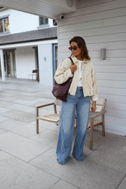 Veste en velours doublée portée par une femme, vue de face, terrasse, sac bordeaux