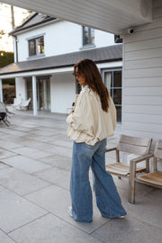 Veste en velours doublée portée par une femme, vue de face, terrasse, jean large