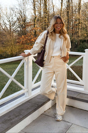 Veste en velours doublée portée par une femme, vue de face, rambarde, pantalon crème