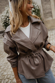 Veste effet cuir ceinturée portée par une femme, vue rapprochée, ceinture nouée