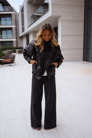 Veste en simili cuir portée par une femme, vue de face, terrasse, mains dans les poches