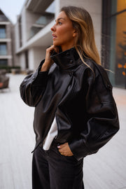 Veste en simili cuir portée par une femme, vue de trois-quarts, téléphone, façade