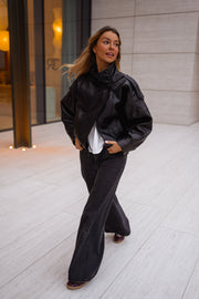 Veste en simili cuir portée par une femme, en marchant, terrasse, pantalon noir