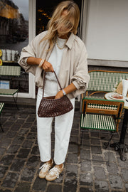 Veste zippée à manches ballon portée par une femme, vue rapprochée, lunettes de soleil, sac marron
