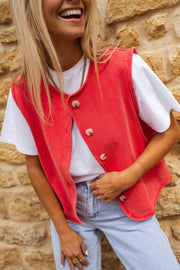 Veste sans manches boutonnée rouge portée par une femme, vue rapprochée, t-shirt blanc, sourire