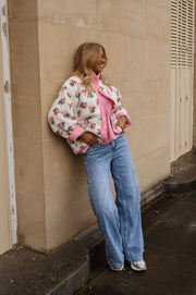 Veste polaire réversible fleurie portée par une femme, vue de trois-quarts, appuyée au mur, jean large