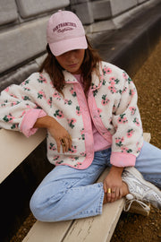 Veste polaire réversible fleurie portée par une femme, assise, banc, casquette rose
