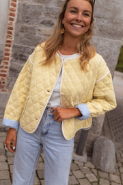Veste matelassée à doublure rayée portée par une femme, vue de face, sourire, doublure bleue